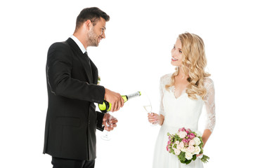 groom pouring champagne while bride holding glass isolated on white