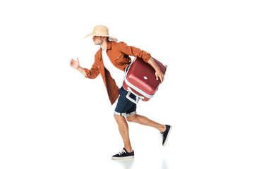 side view of tourist in straw hat running with travel bag isolated on white