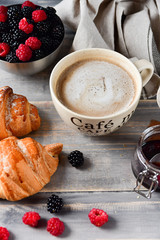 Breakfast at the European hotel: coffee with milk and croissants, jam and fresh raspberries and blackberries on a wooden table. on the Cup inscription in French (mocha coffee, coffee with milk)