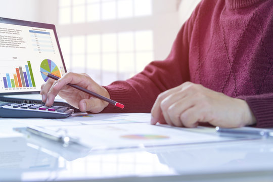 Man In Red Casual Sweater Is Deeply Reviewing A Financial Report For A Return On Investment Or Investment Risk Analysis.