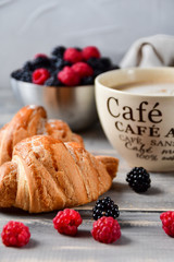 Breakfast at the European hotel: coffee with milk and croissants, jam and fresh raspberries and blackberries on a wooden table. on the Cup inscription in French (mocha coffee, coffee with milk)