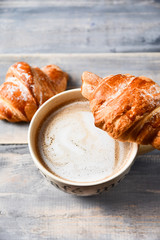  Breakfast is a large beige Cup of coffee with milk and croissants on a wooden table. on the Cup inscription in French (top down: mocha coffee, coffee with milk, coffee without sugar)