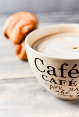  Breakfast is a large beige Cup of coffee with milk and croissants on a wooden table. on the Cup inscription in French (top down: mocha coffee, coffee with milk, coffee without sugar)