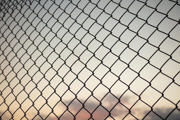 Fototapeta premium Sky through wire mesh fence. Blur background, close up view of link cage.