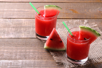 Watermelon smoothies with watermelon slices on a brown wooden table with a place for inscription