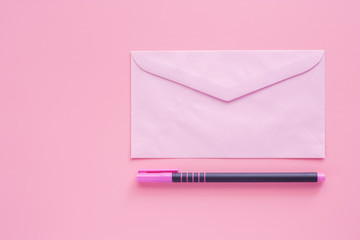 Pink envelope with a pen for enclose a letter or document on pink background