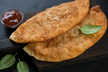 Closeup of chebureki or deep-fried crescent shape pies filled with ground meat and onion, selective focus