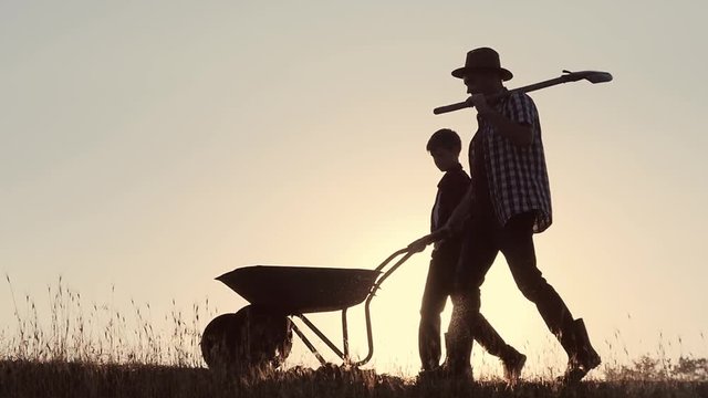 Happy family father and son harvesting in the field at sunset