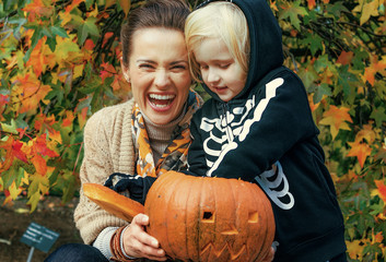 mother and daughter playing with carved Halloween pumpkin