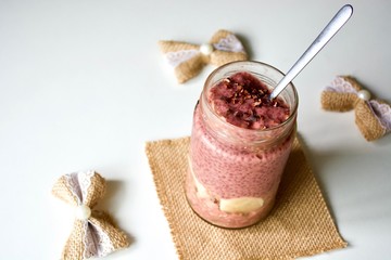 Tasty raspberry chia pudding in a jar on the white table.