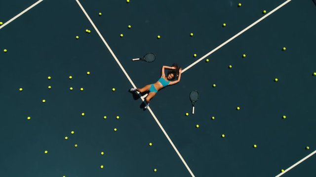 the girl in sports lingerie lies on the tennis court.