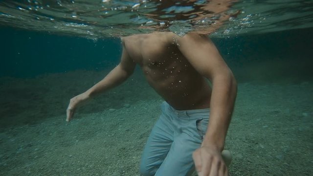 Young Attractive man floating under the water in the sea. Male model on the shore. Slow motion, Underwater shooting
