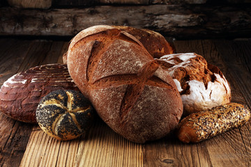 Different kinds of bread and bread rolls on board from above. Kitchen or bakery