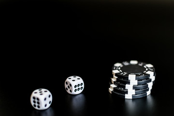 dice and monochrome casino chips on black background