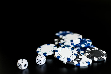 dice and colored casino chips on a black background