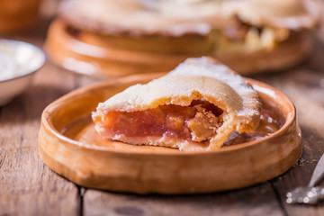 Piece of fresh rhubarb and strawberry pie with cream nearby