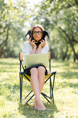 Business woman with a laptop in the Park sitting on a folding chair with her shoes in her hands