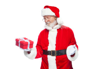Christmas. Smiling Santa Claus in white gloves is holding a gift red box with a bow. Pointing at the gift. Isolated on white background.