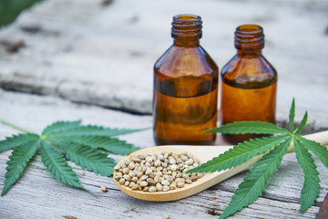 hemp leaves on wooden background, seeds, cannabis oil extracts jars