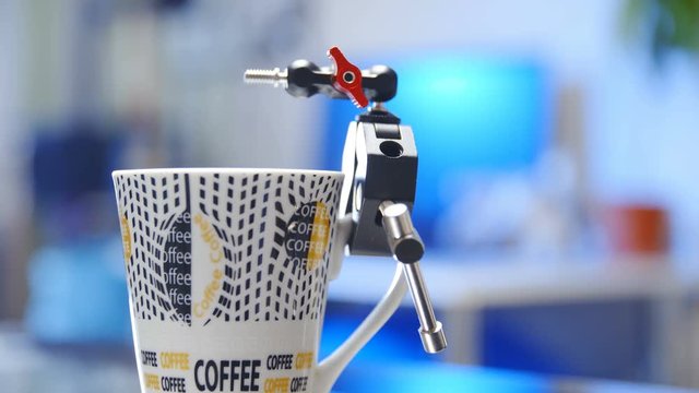 Crab clamp magic arm holding to coffee cup slide out 4K. Dolly slide shot refocus from blurred background to magic arm equipment in focus.