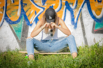Portrait of young beautiful woman wearing white tank shirt and blue jeans and black hat on brick...