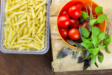 pasta,tomatoes and fresh basil leaves on a wooden cutting board