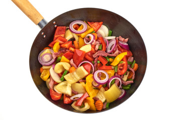 Fried vegetables in a frying pan, isolated on white background