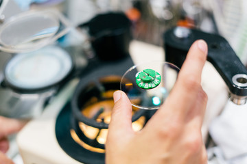Female optician measuring and preparing glasses on the latest digital device in optical store....