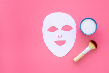 Cosmetic product for cleansing skin. Facial mask, cream and brush on pink background top view space for text