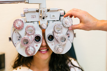 Smiling woman doing eyesight measurement with optical phoropter