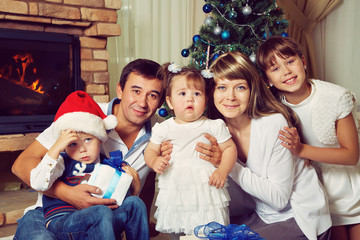 family celebrating Christmas at home on the background of the Christmas tree