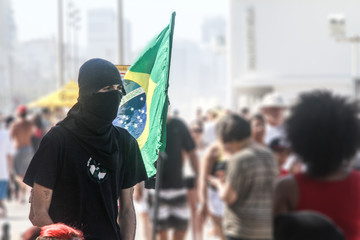 anarchist black-bloc man and a brazilian flag - obrazy, fototapety, plakaty