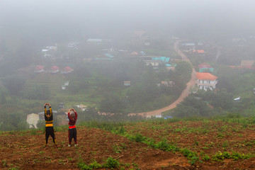 The Two boy wearing a Hmong dress with their village in nature forest which has foggy at Phuhinrongkla National Park Nakhon Thai District in Phitsanulok, Thailand.