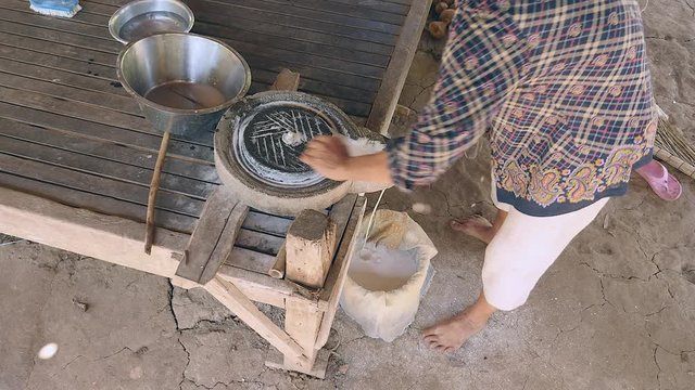  Upper view on woman cleaning up soaked rice flour from millstone