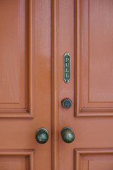 Red doors with ornate framing, old knobs and a pull sign