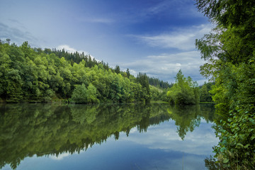 Obraz na płótnie Canvas Grüne Bäume und ein blauer Himmel am Rösper Weiher
