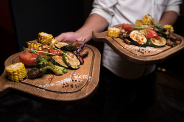 two portions baked vegetables on a wooden tray
