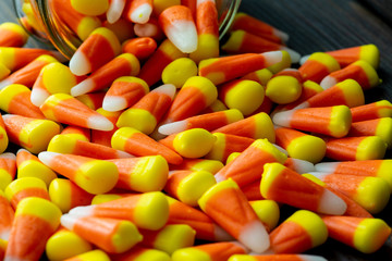 Halloween theme featuring a spilling of candy corn from a jar not a wooden table.