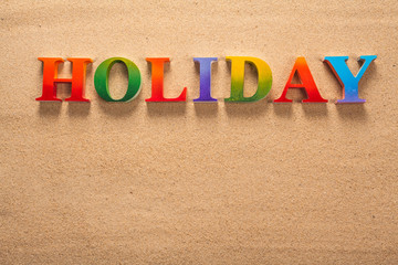 holiday written in colorful letters on the beach with copy space