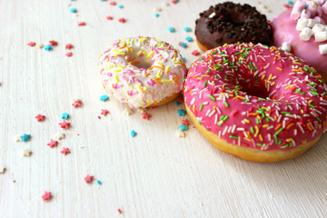 Photos of different donuts. Assorted colorful donuts in pink, green, chocolate icing close-up, sweet dessert.