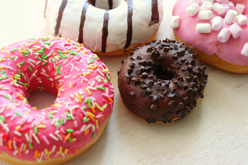 Photos of different donuts. Assorted colorful donuts in pink, green, chocolate icing close-up, sweet dessert.
