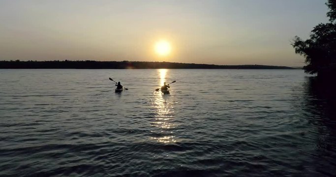 Two kayaks with people on the river on the scenic sunset