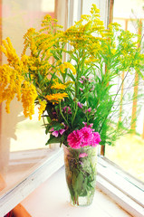 Different summer meadow flowers. Rustic interior.