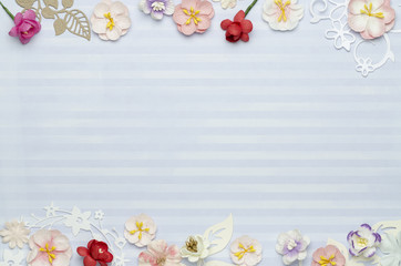 Paper colored flowers on the edges, blue background with stripes and blank space in the center. Top view