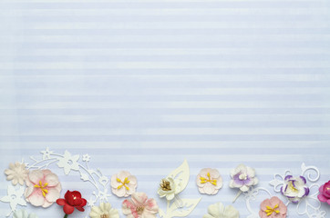 Beautiful paper flowers at the bottom of the frame, a blank blue background in the center. Top view
