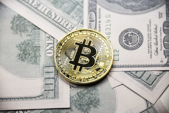Gold coin Bitcoin on the background of hundred dollar bills