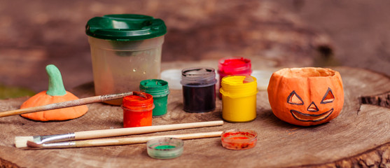 Preparation of autumn decor. Pumpkin candlestick to the Halloween, jars with paint of different colors and brushes. Handmade