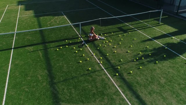 blonde girl lies on a tennis court.