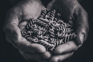 Rough rough masculine hands hold Italian pasta - black and white