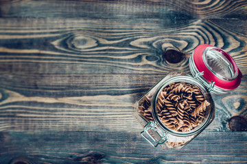 Glass jar with pasta on a wooden kitchen table - top view - copy space